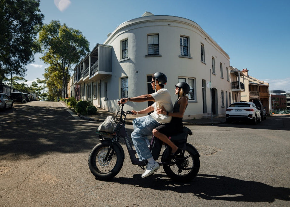 Two people riding a electric bike on a street