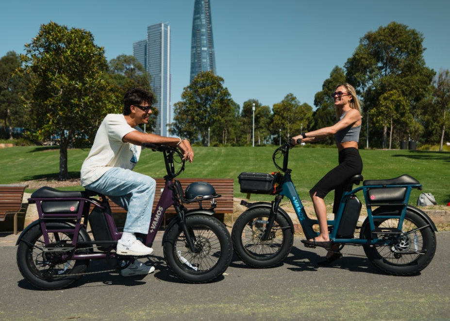 Two people riding electric bikes in a park