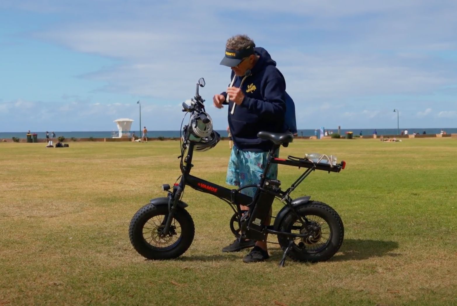 A black El Doblez Foldable Ebike compactly folded and stored indoors next to a modern floor lamp