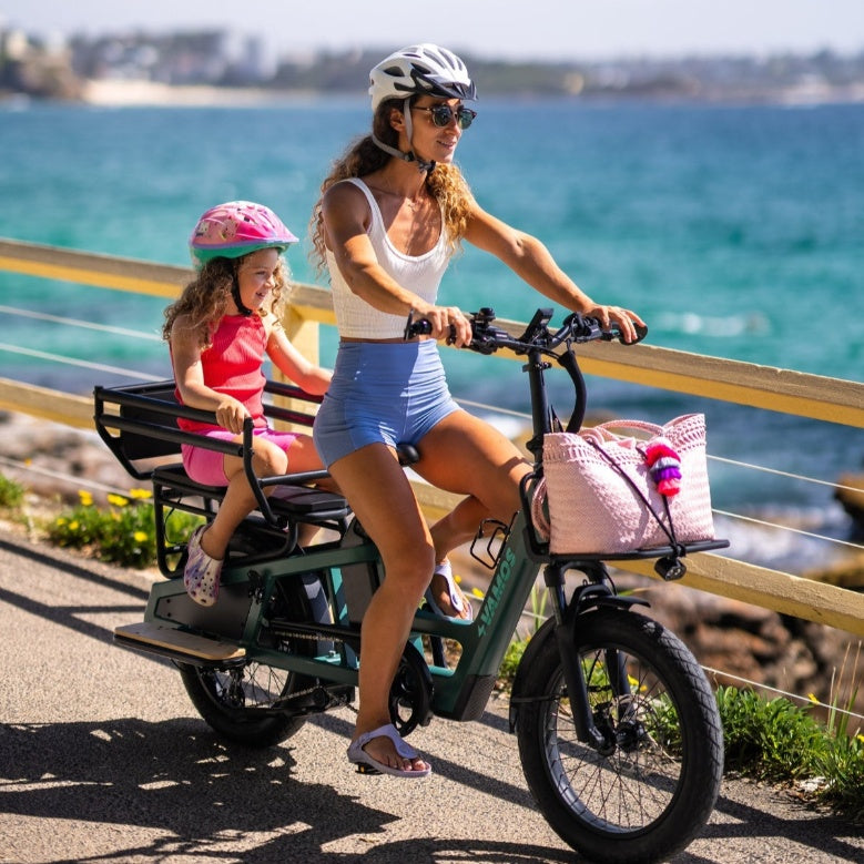 Woman and child riding an electric bike by the sea