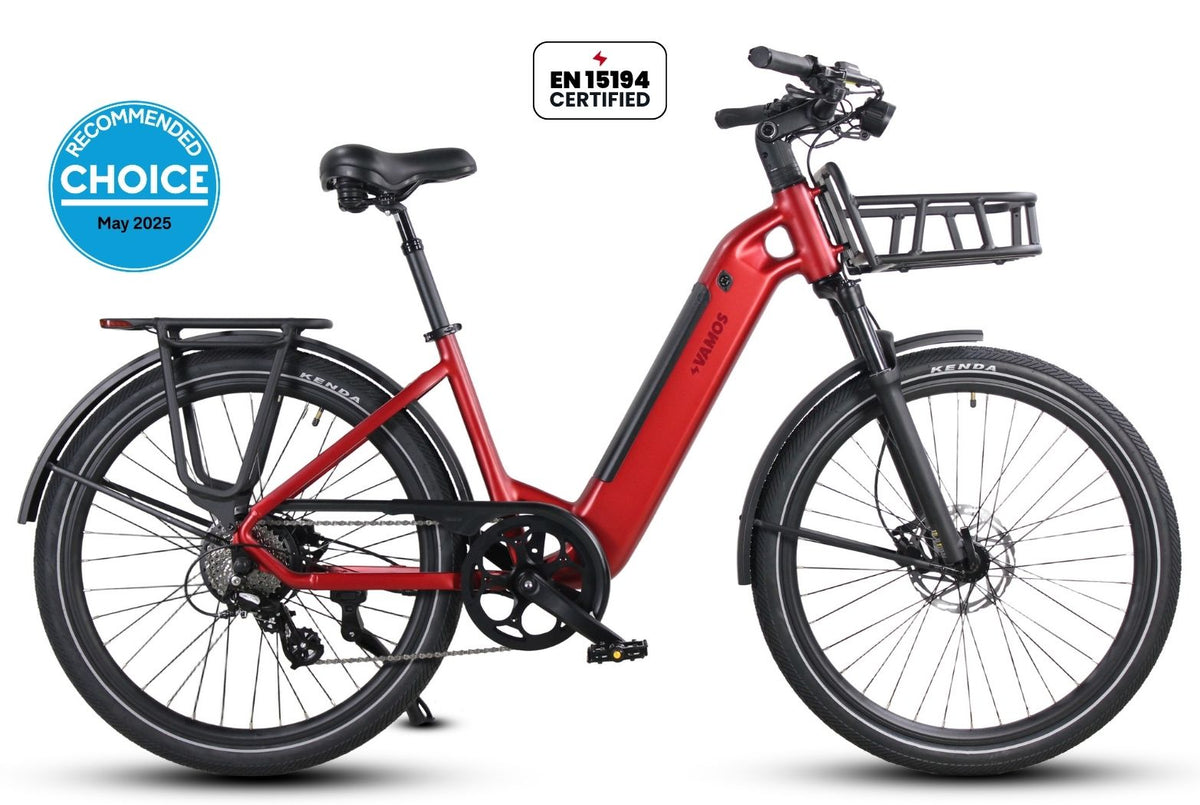A red and black electric bicycle shown in a side profile on a white background, featuring a front basket, rear rack, fenders, and certification badges including EN15194 Certified and a blue Recommended Choice badge.