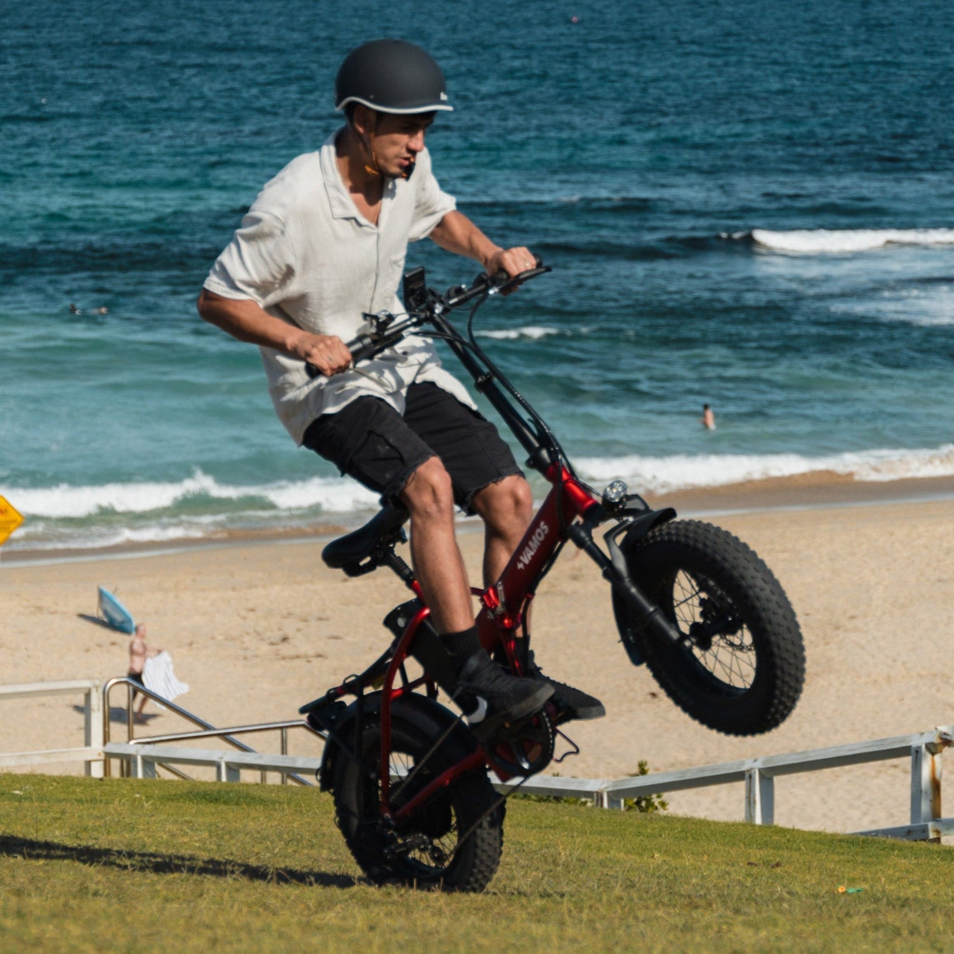 Person riding a fat-tire bike on a grassy area near the beach